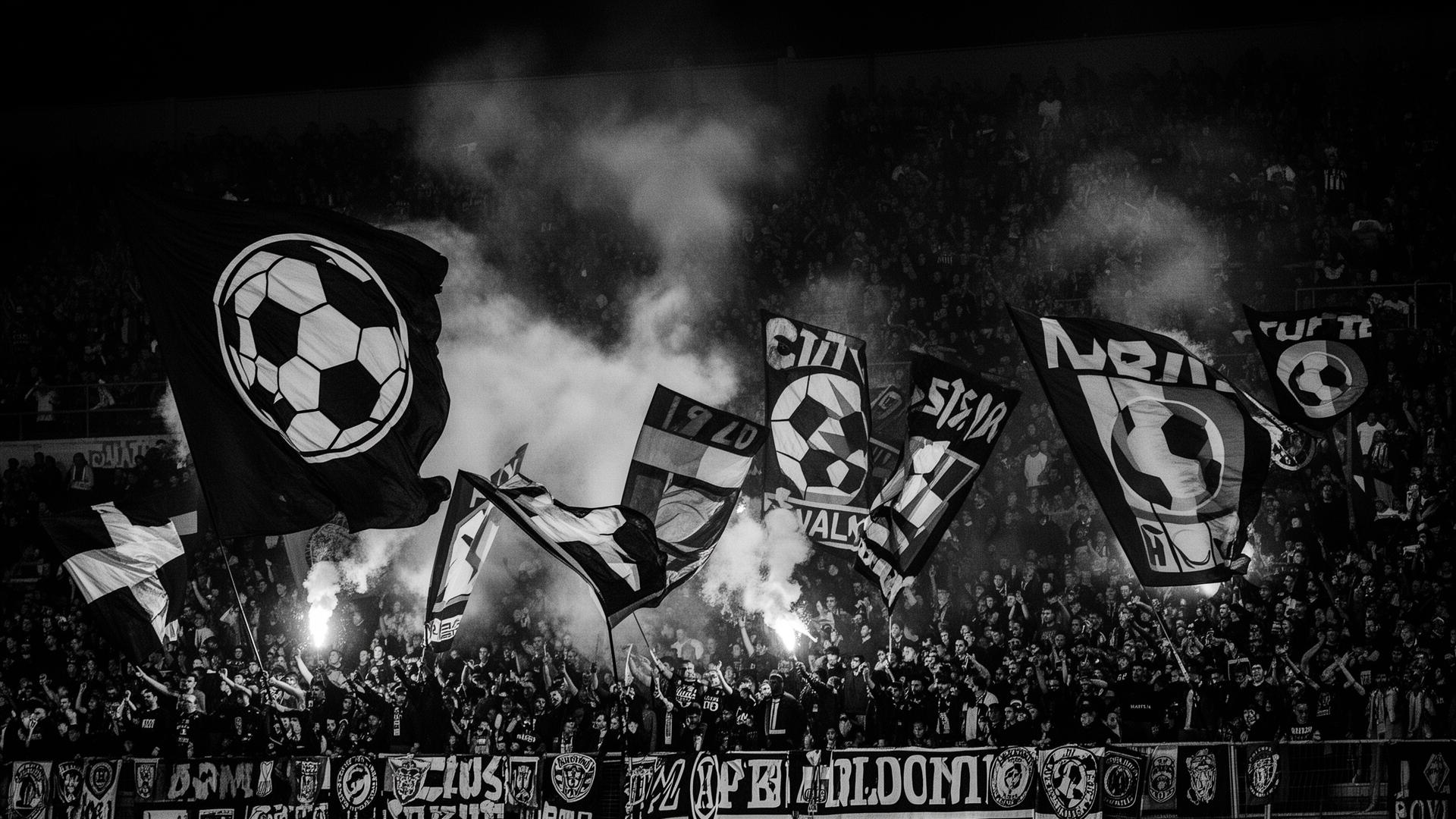 Football supporters in a packed stadium waving custom flags
